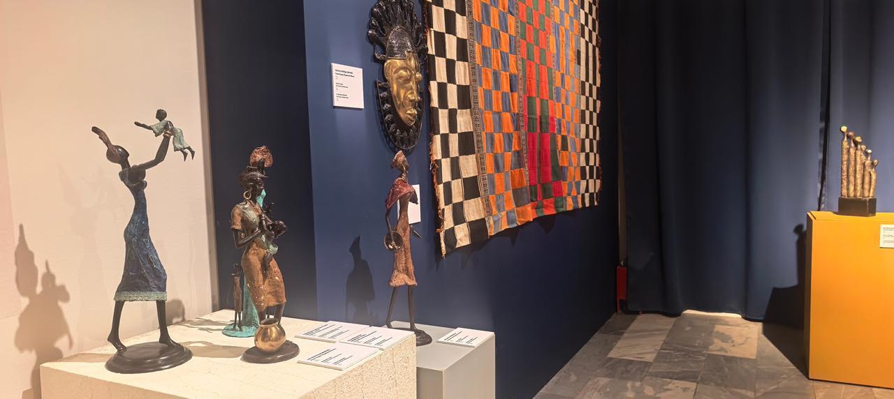 Bronze figures from Burkina Faso and a woven cloth on display at the exhibition